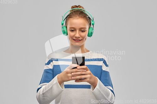 Image of smiling teenage girl in headphones with smartphone