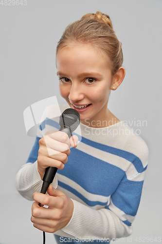 Image of smiling teenage girl with microphone singing