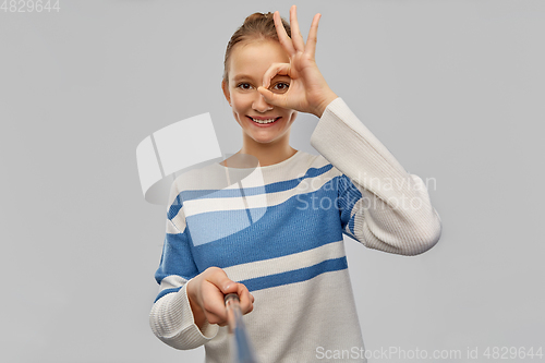 Image of smiling teenage girl in pullover taking selfie