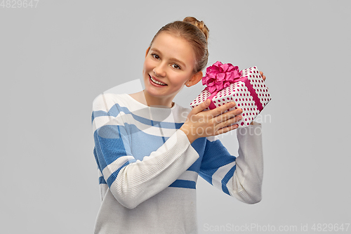 Image of smiling teenage girl in pullover with gift box