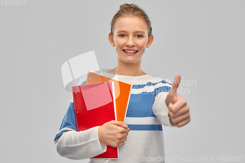 Image of smiling teenage student girl showing thumbs up