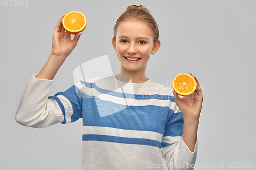 Image of smiling teenage girl in pullover with oranges