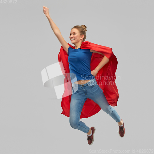 Image of smiling teenage girl in red superhero cape jumping