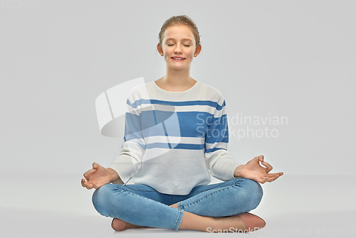 Image of smiling teenage girl meditating in lotus pose