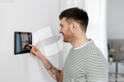 Image of smiling man using tablet computer at smart home