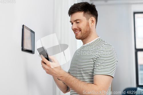 Image of smiling man using tablet computer at smart home