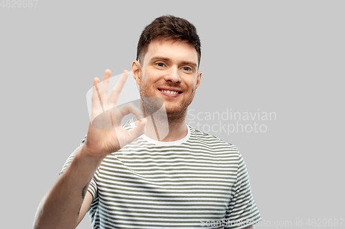 Image of young man showing peace over grey background