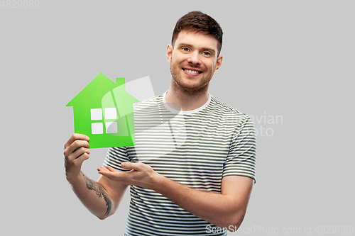 Image of smiling young man holding green house icon