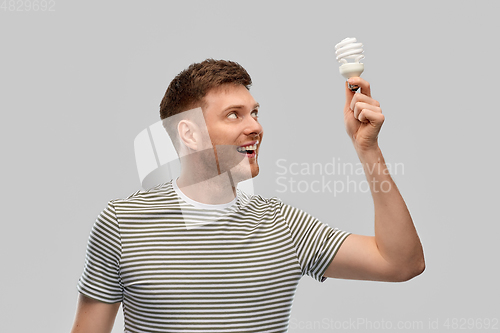 Image of smiling young man holding lighting bulb
