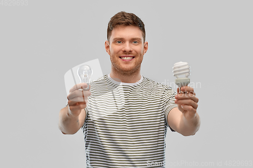 Image of smiling young man comparing different light bulbs