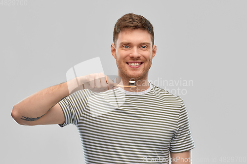 Image of smiling man with toothpaste on wooden toothbrush