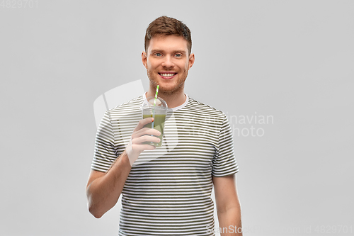 Image of man drinking green smoothie from disposable cup