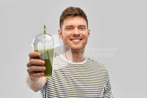 Image of man drinking green smoothie from disposable cup