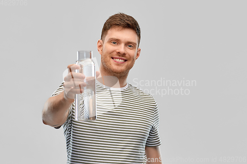 Image of happy smiling man holding water in glass bottle