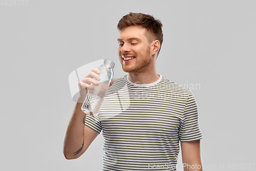 Image of happy smiling man drinking water from glass bottle