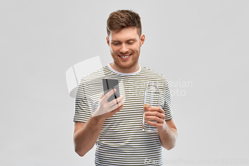 Image of man with smartphone and water in glass bottle