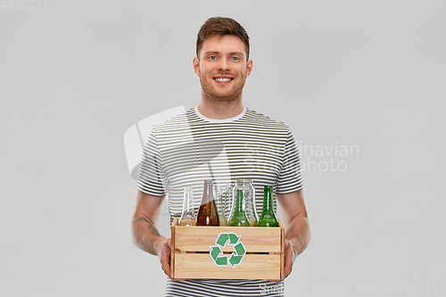 Image of smiling young man sorting glass waste