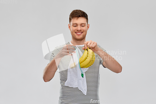 Image of smiling man putting bananas into reusable net bag