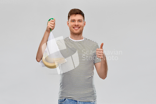 Image of happy man holding reusable string bag with bananas