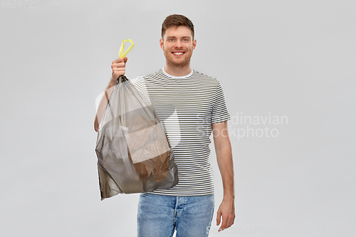 Image of smiling man holding trash bag with paper waste