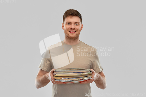 Image of smiling young man sorting paper waste