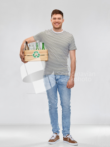 Image of smiling young man sorting glass waste