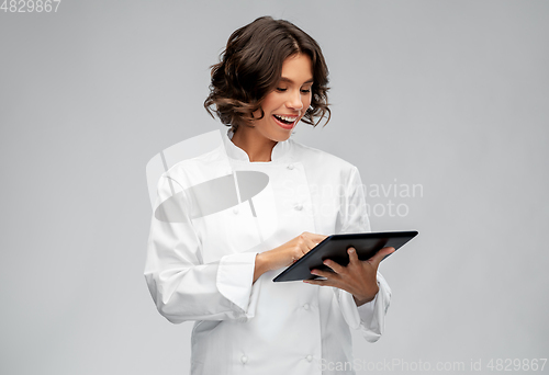 Image of smiling female chef in toque with tablet computer