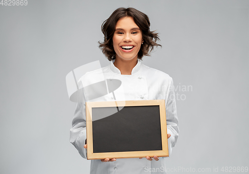 Image of smiling female chef holding black chalkboard