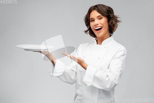 Image of smiling female chef holding empty plate