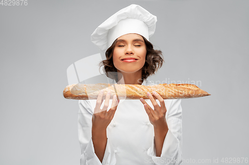 Image of happy female chef with french bread or baguette