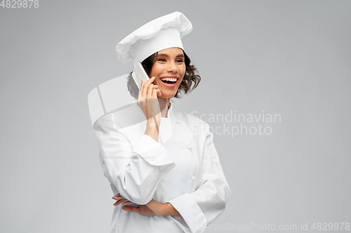 Image of smiling female chef in toque calling on smartphone