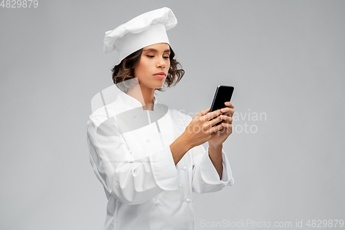 Image of female chef in toque with smartphone