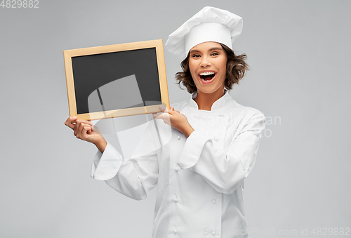 Image of smiling female chef holding black chalkboard