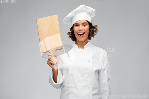 Image of smiling female chef in toque with cutting board