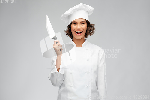Image of smiling female chef in toque with kitchen knife