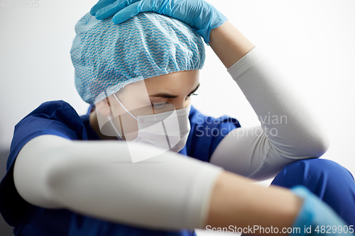 Image of sad doctor or nurse in face mask holding to head