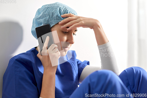 Image of sad doctor or nurse calling on smartphone