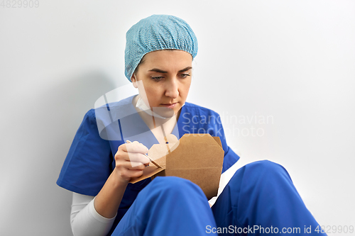 Image of sad doctor or nurse eating takeaway food from box