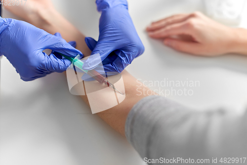 Image of doctor taking blood for test from patient's hand