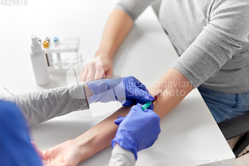 Image of doctor taking blood for test from patient's hand