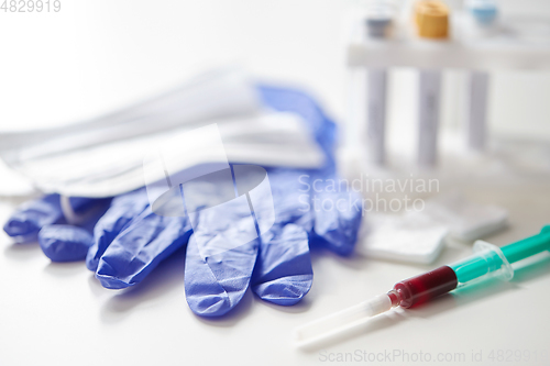 Image of close up of blood in syringe, gloves and mask