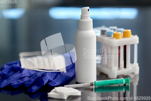 Image of syringe, beakers with blood test, gloves and mask