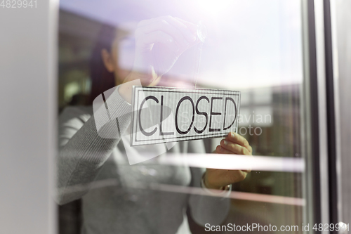 Image of woman hanging banner with closed word on door
