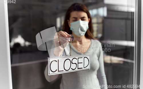 Image of woman in mask hanging banner closed on door