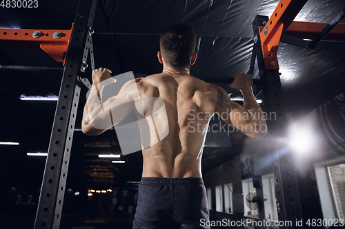 Image of Young healthy male athlete doing exercises in the gym