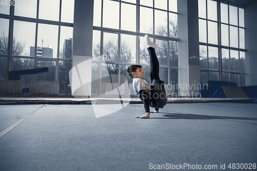 Image of Little male gymnast training in gym, flexible and active