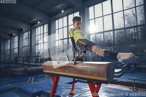 Image of Little male gymnast training in gym, flexible and active