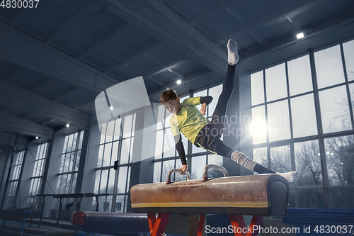 Image of Little male gymnast training in gym, flexible and active