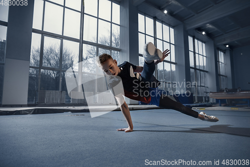 Image of Little male gymnast training in gym, flexible and active