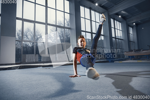 Image of Little male gymnast training in gym, flexible and active